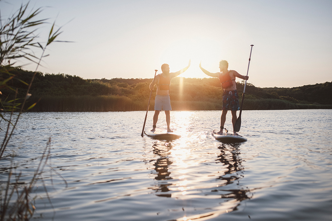 Zwei Stand up Paddler geben sich High Five – viele Wassersportaktivitäten sind am Bodensee möglich
