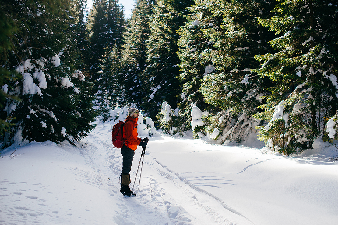 Mann steht mit Wanderstöcken im Schnee auf einem der schönsten Berge Deutschlands 