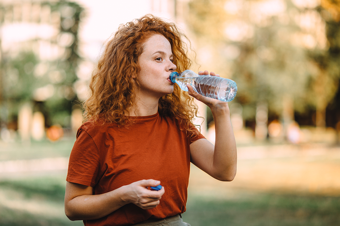 Frau trinkt Wasser – genügend Flüssigkeit beugt Schulstress vor