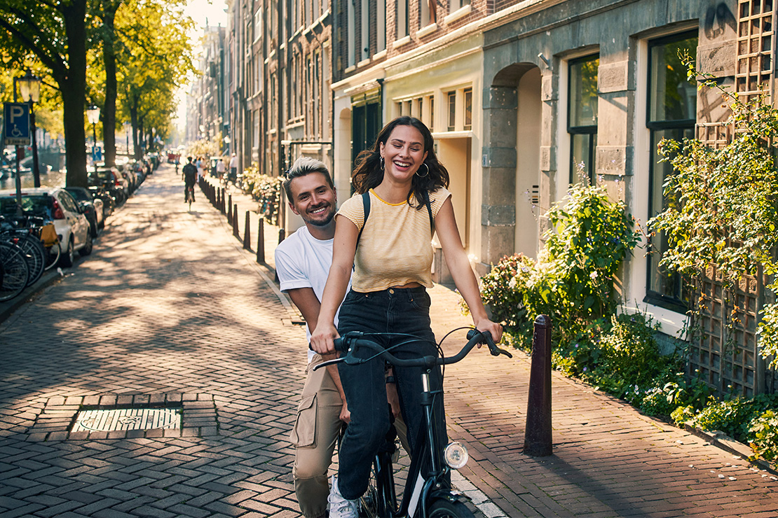 Pärchen fährt beim Tagesausflug zu zweit auf dem Fahrrad durch die Stadt