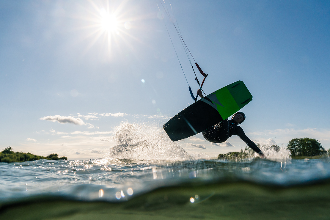 Freizeit-Aktivitäten auf Rügen: Kitesurfer bei Sprung über das Wasser