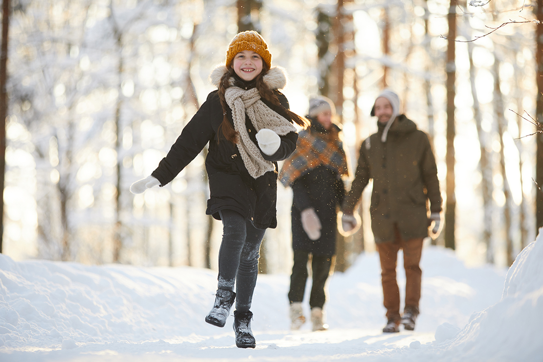 Kind läuft mit Eltern bei Winterwanderung durch den Schnee